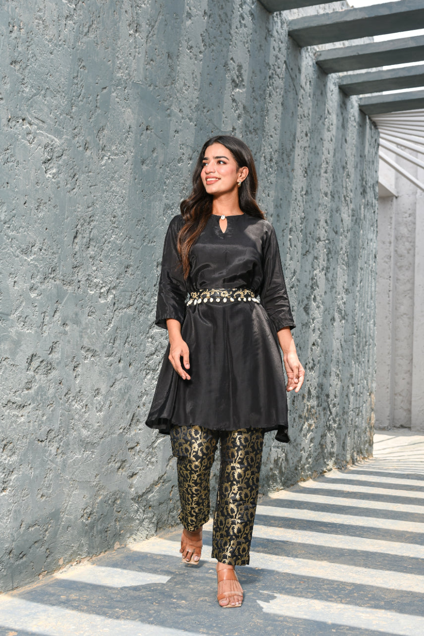 Woman in black outfit with leopard print pants walking along a stone pathway.
